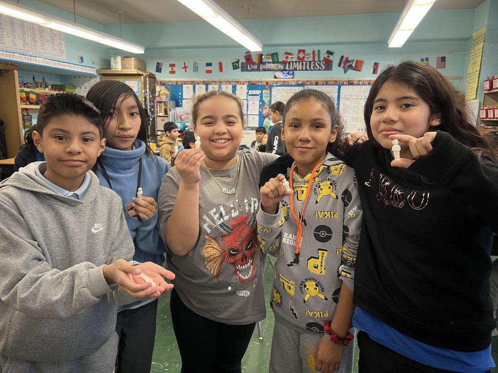 Five children showing small items in their hands while smiling.